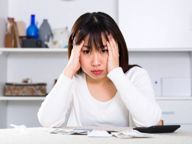 家計簿を付けながら悩んでいる主婦
