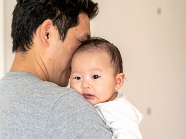赤ちゃんの匂いを嗅いで微笑んでいる父親