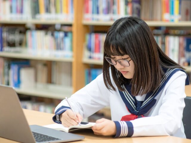 ノートパソコンを開いて勉強する女子学生