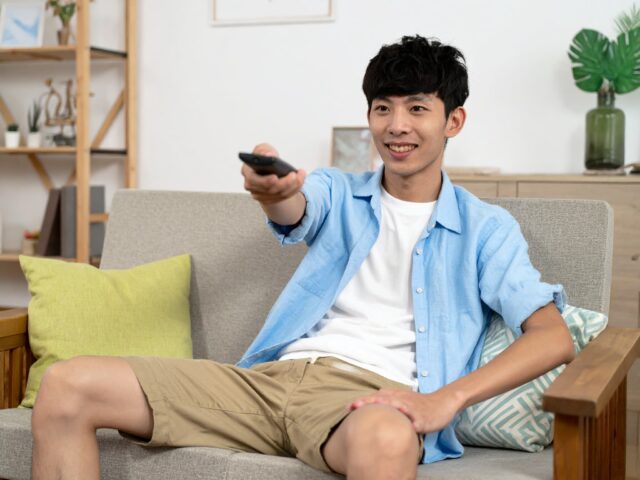 テレビのチャンネルを変更する若い男性