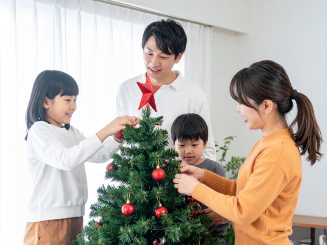クリスマスツリーの飾り付けをする家族