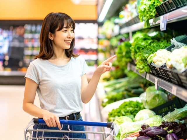 スーパーマーケットで野菜を選ぶ女性