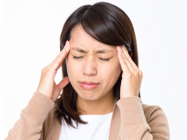 体調不良とめまいでつらそうな表情を浮かべる女性