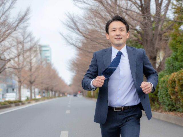 スーツ姿のビジネスマンが街中を走る様子