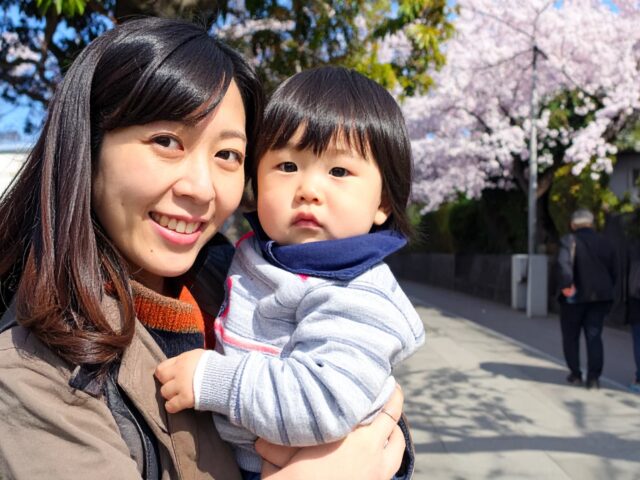 桜の季節、子どもを抱っこする母親