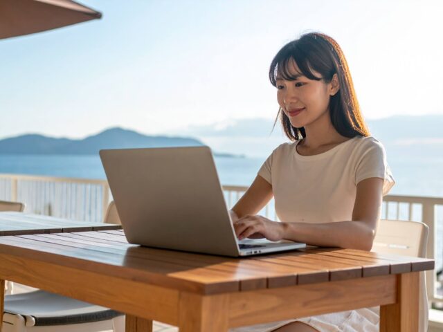 海の見えるテラスでリモートワークする女性