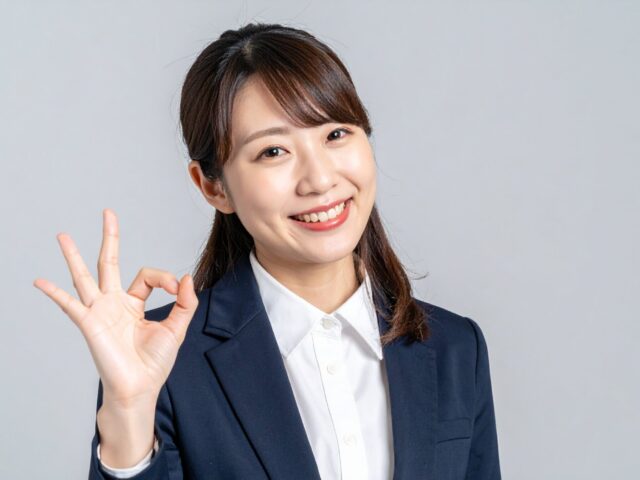 笑顔でOKサインを出すスーツ姿の日本人女性