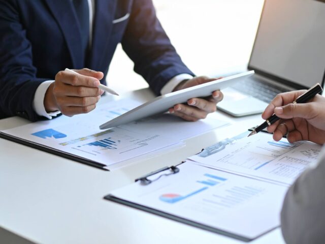 オフィスでタブレットと資料を見ながら会議をするビジネスパーソン