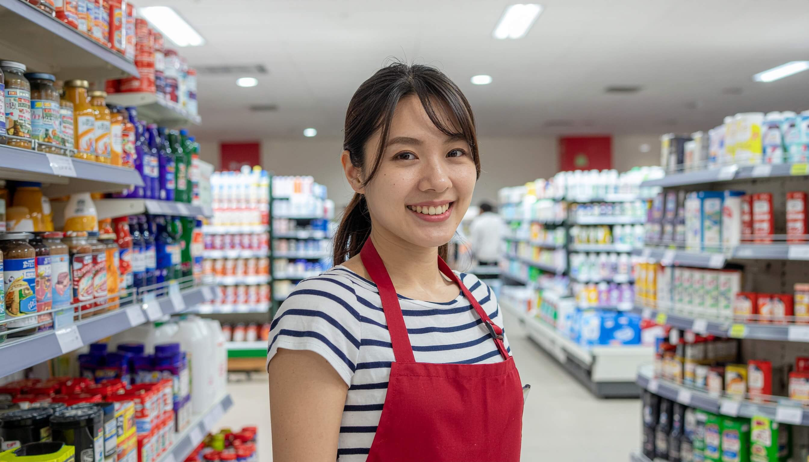 スーパーマーケットのレジで働く笑顔の若い女性