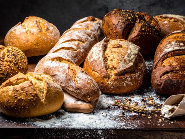 木製のテーブルに並べられた種類の異なる焼きたてのハード系パン