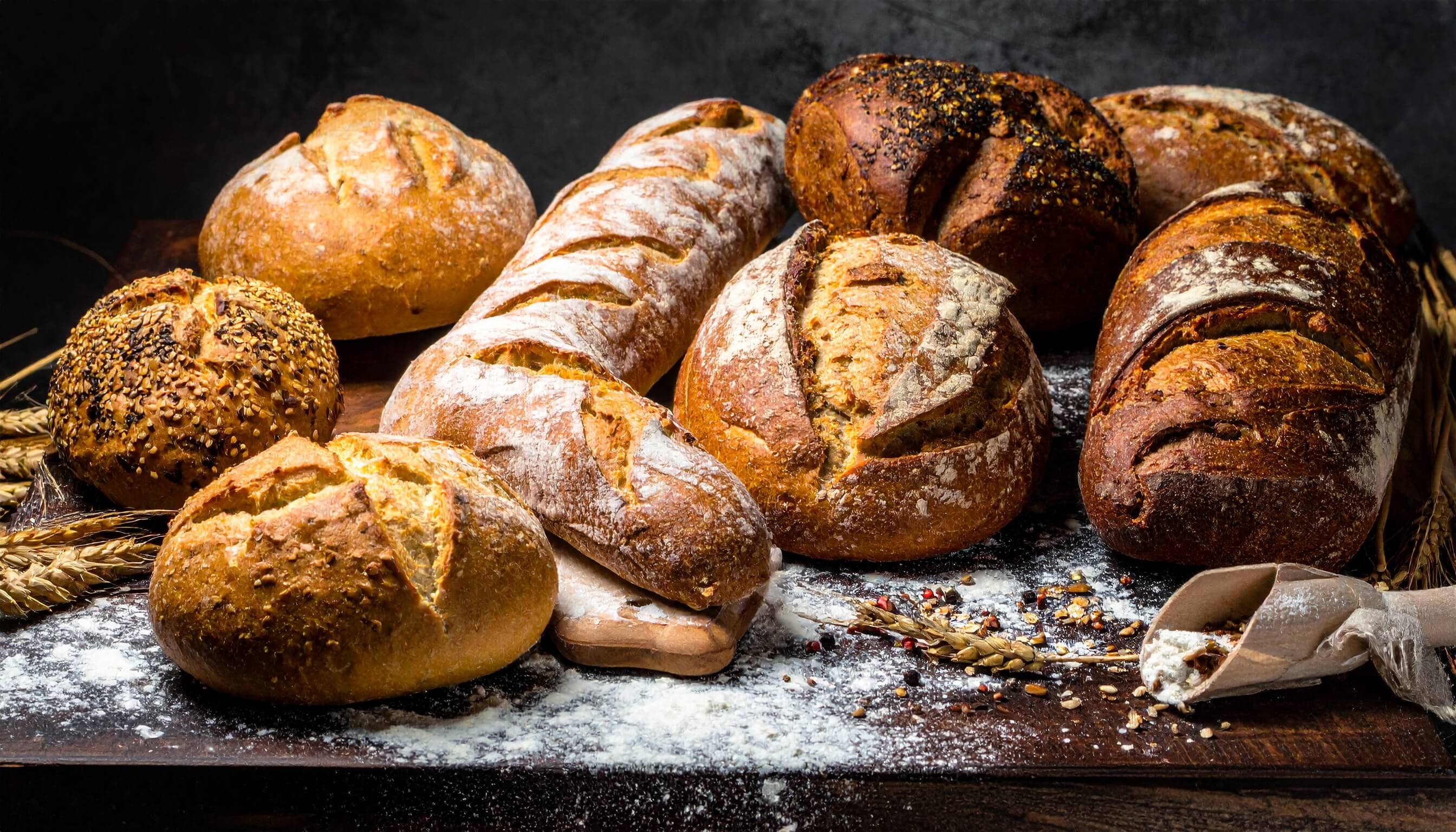 木製のテーブルに並べられた種類の異なる焼きたてのハード系パン