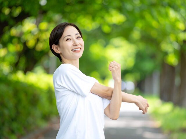 新緑の公園で運動前にストレッチをして体をほぐす女性