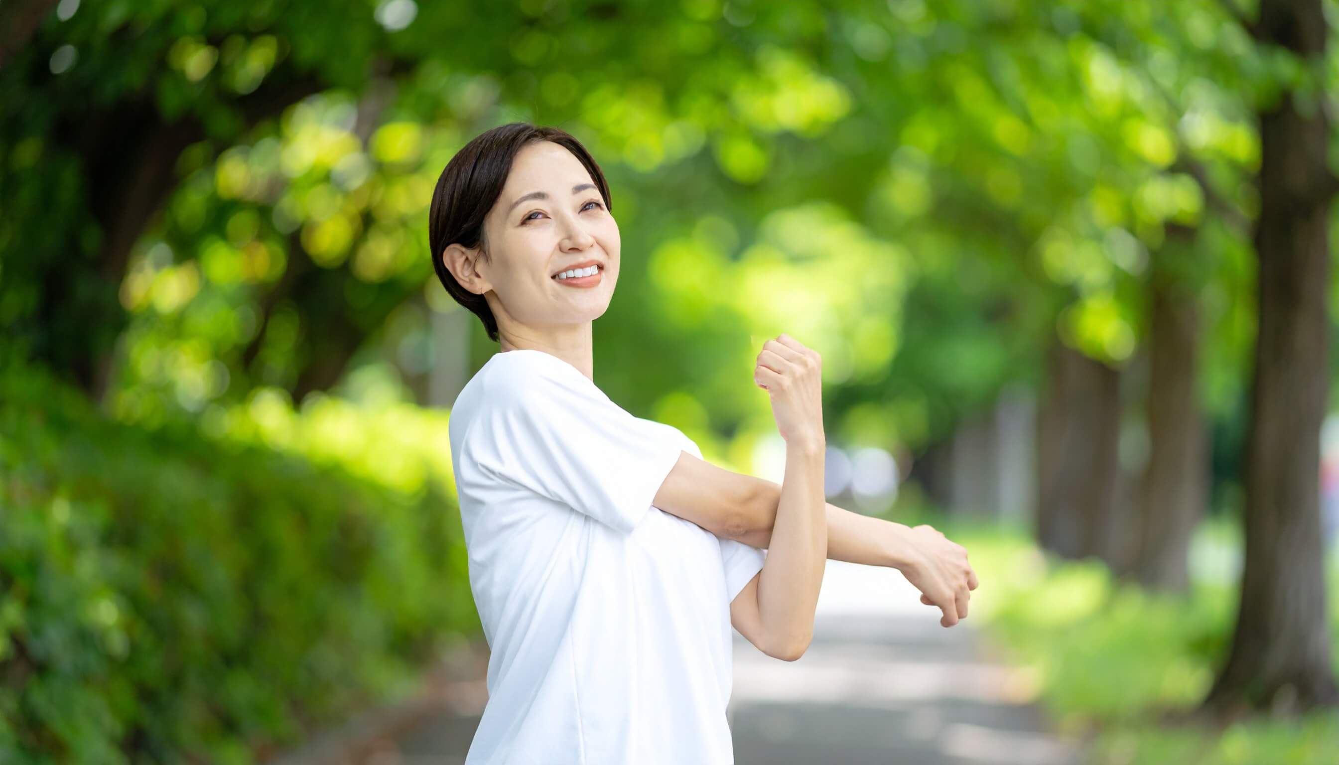 新緑の公園で運動前にストレッチをして体をほぐす女性