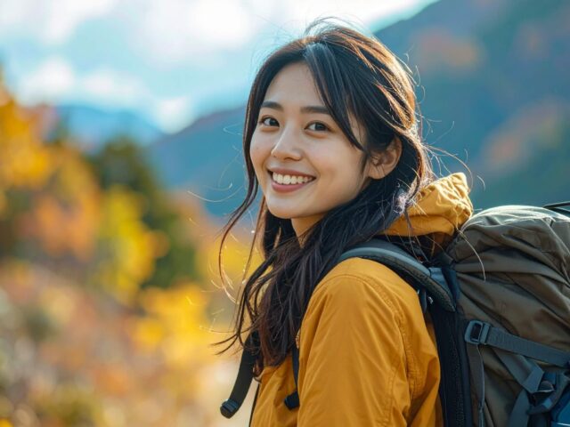 秋の山でハイキングを楽しみながら振り返る笑顔の女性