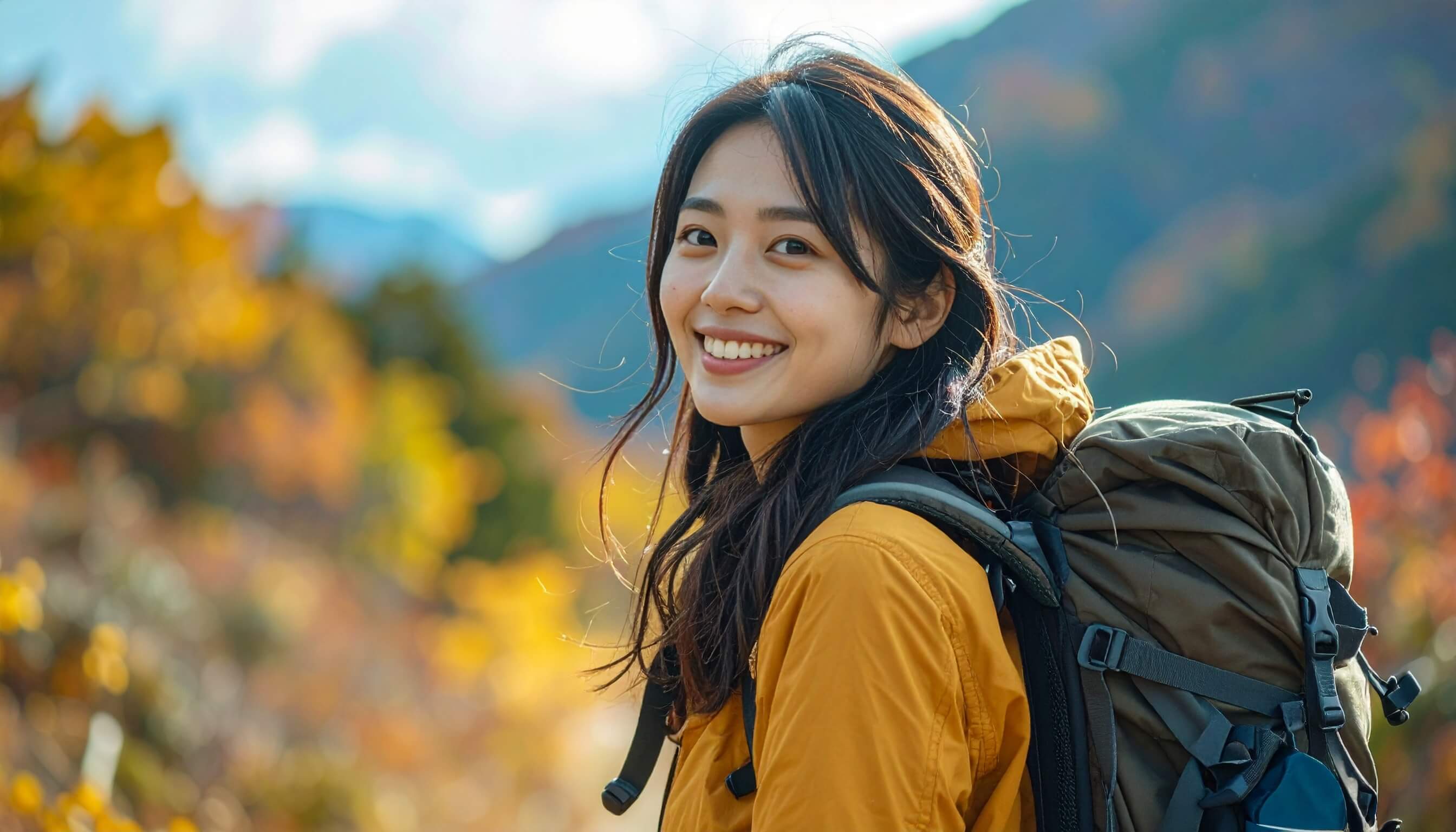 秋の山でハイキングを楽しみながら振り返る笑顔の女性