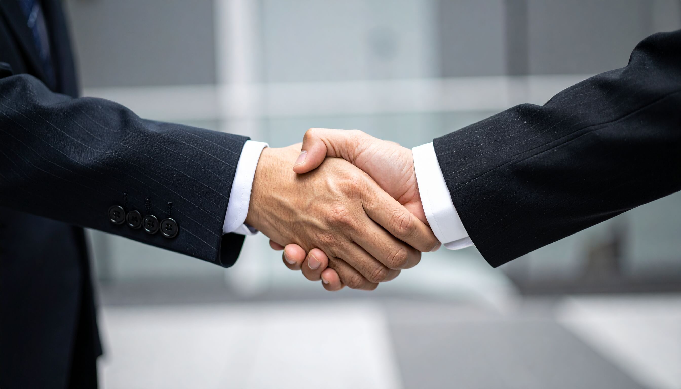 契約成立を祝してがっちりと握手を交わすビジネスマンの手元