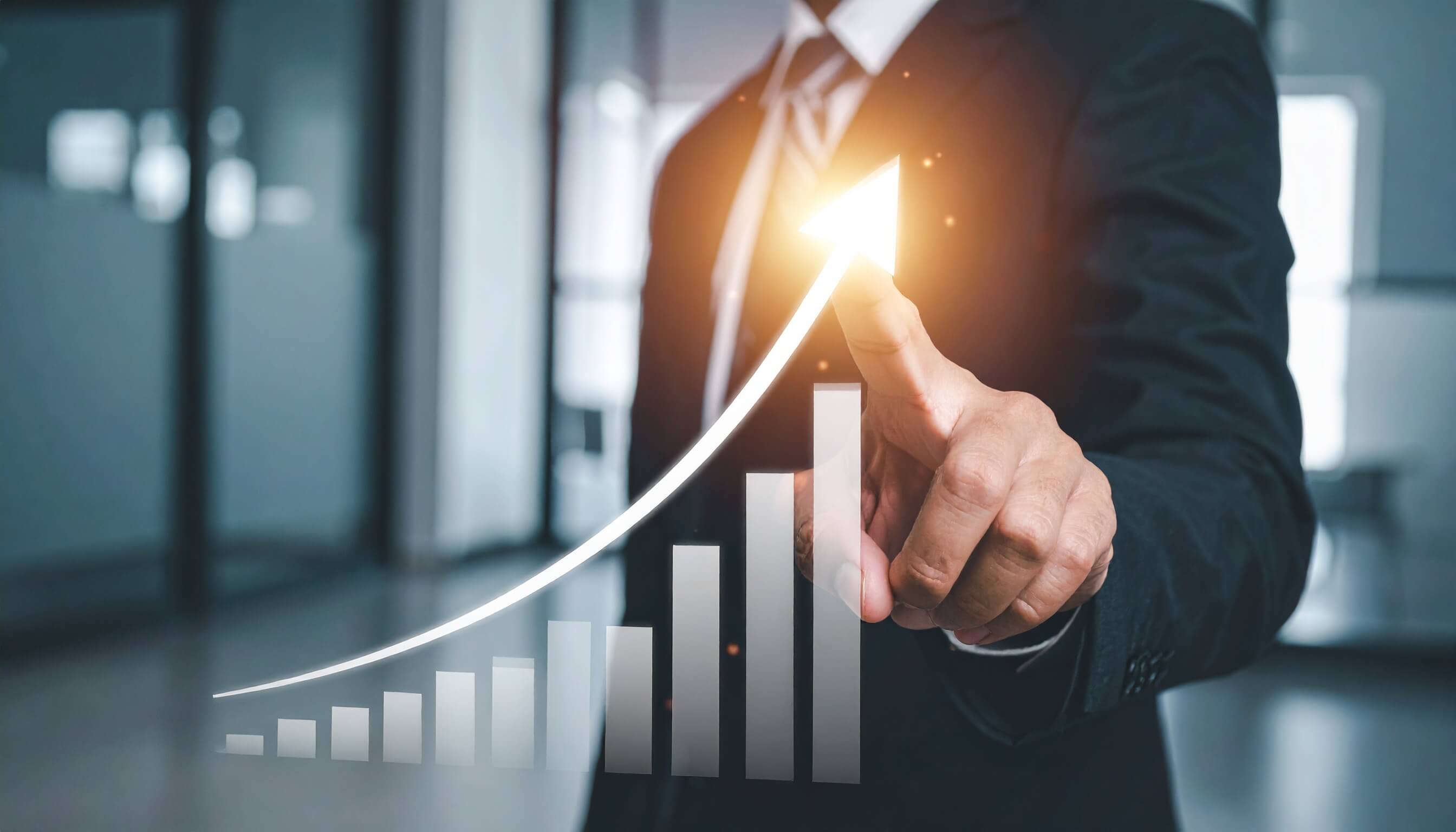 業績の右肩上がりと成長を示す矢印を指差すビジネスマン