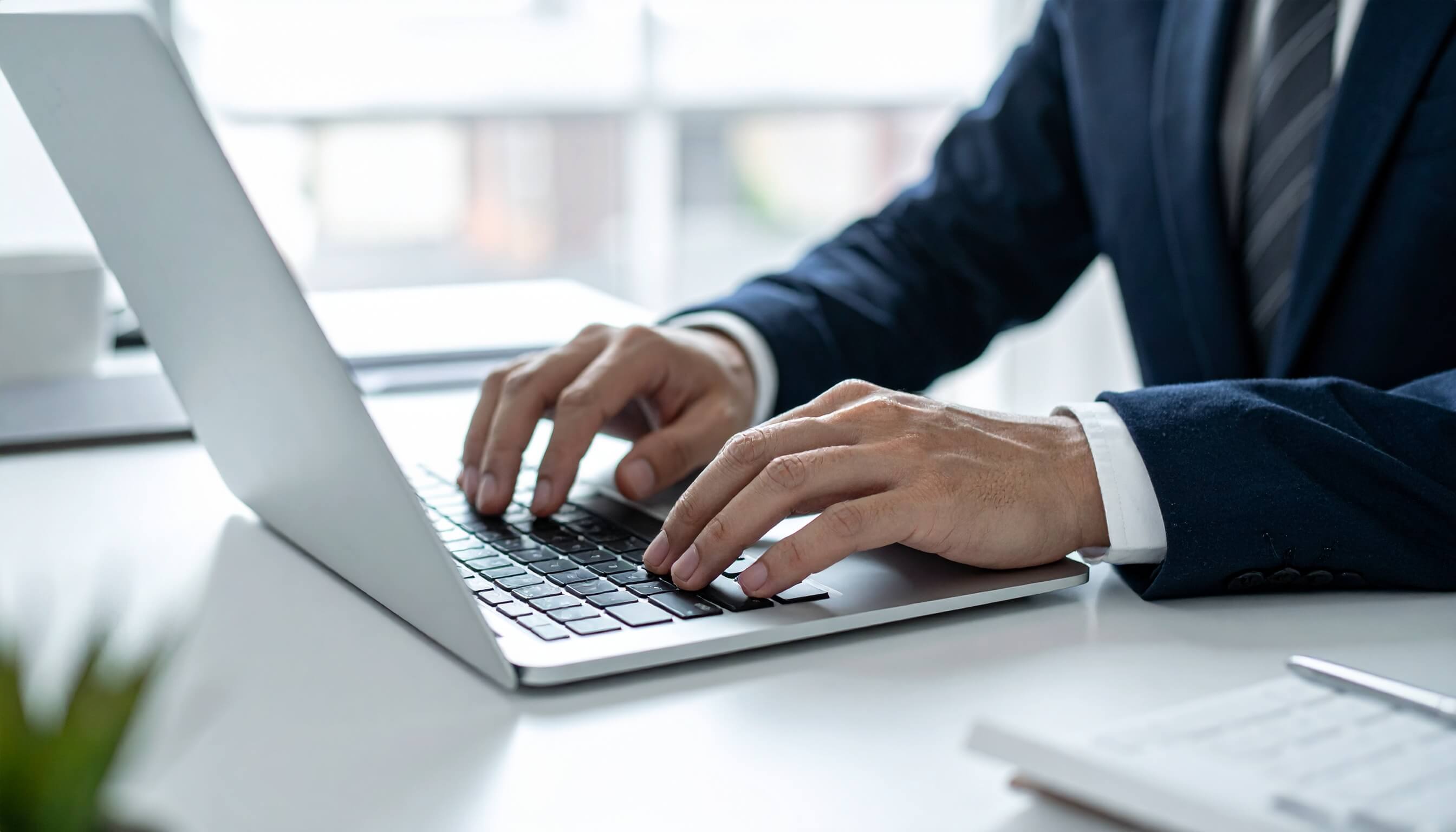 オフィスでノートパソコンをタイピングするビジネスマンの手元